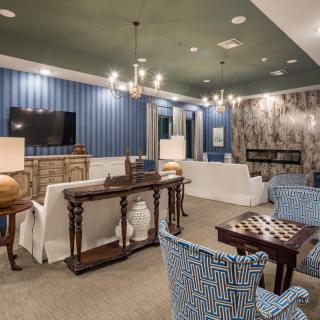 A stylish and modern living room with blue accents, featuring elegant chandeliers and comfortable seating.