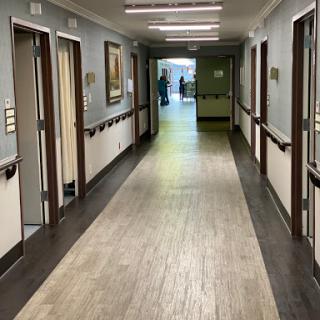 A well-lit hallway in a healthcare facility, with doors leading to individual rooms.