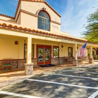 A sunny day view of a building with an American flag at the entrance.