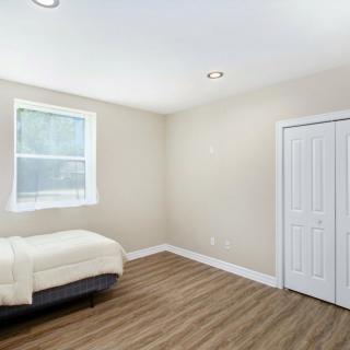 A minimalist bedroom with a single bed, wooden flooring, and beige walls.