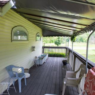 A covered porch with outdoor seating in a rural setting.