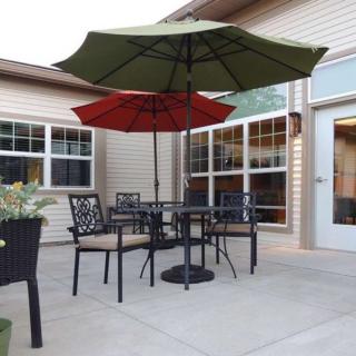 A cozy patio setup with a table, chairs, and two umbrellas providing shade.