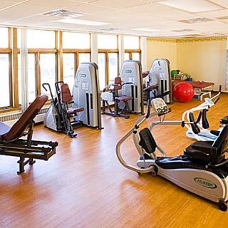 A well-lit gym room equipped with various exercise machines and fitness equipment.