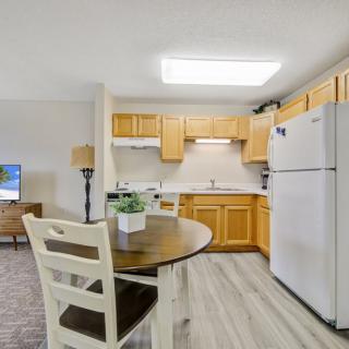 A modern kitchen with wooden cabinetry, a dining table, and chairs.