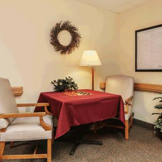 A cozy seating area with two chairs and a table, adorned with a wreath and a lamp.