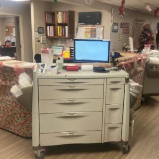 A medical cart with a computer at a hospital nurse station.