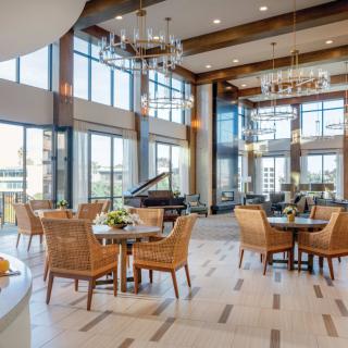 A modern dining area with large windows, natural light, and elegant chandeliers.