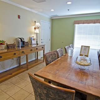 A cozy dining area with a wooden table and chairs, complemented by a coffee station in a well-lit room.