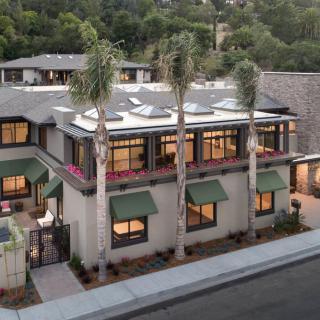 Modern residential building with palm trees lining the street.