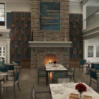 A cozy restaurant dining area featuring a large stone fireplace and elegantly set tables.