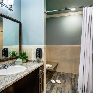 A modern bathroom with a granite countertop and a walk-in shower.