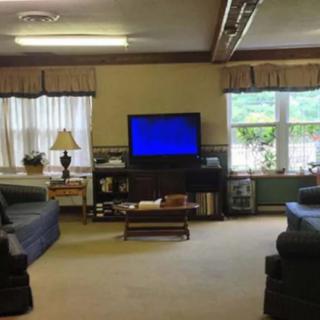 A cozy living room with two couches, a television, and large windows.