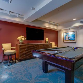 A stylish game room featuring a pool table, seating area, and a large television.