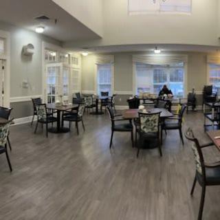 Empty dining area with tables and chairs set up near large windows.