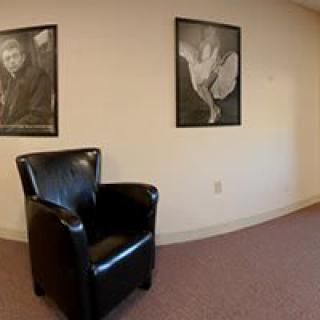 A black leather chair in a room with art portraits on the wall.
