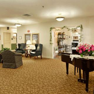 A cozy living room with a piano and seating area, featuring elegant decorations.