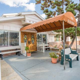 A welcoming house entrance with an orange awning, potted plants, and outdoor seating.