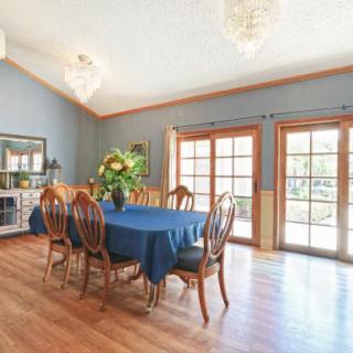 A spacious dining room with a blue tablecloth, wooden chairs, and ample natural light from large French doors.