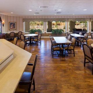 An empty dining area with neatly arranged tables and chairs, featuring large windows that allow natural light to fill the space.