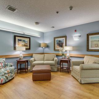 A cozy living room with sofas, armchairs, and decorative artwork on the walls.