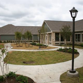 A modern building with a landscaped garden and pathway under a cloudy sky.