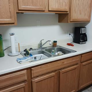 A typical kitchen scene featuring a sink with dirty dishes and wooden cabinets.