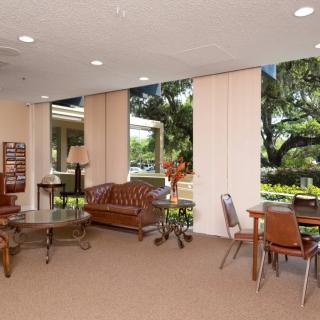 A spacious lobby interior with comfortable seating, tables, and large windows allowing natural light.