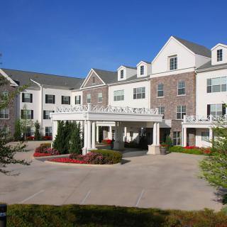 A large residential building with a landscaped entrance and driveway.