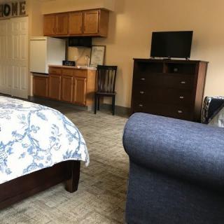A cozy hotel room featuring a bed, small kitchenette, and a television.