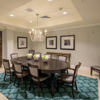 A stylish dining room featuring an oval table, surrounded by chairs and accented with a chandelier and decorative rug.