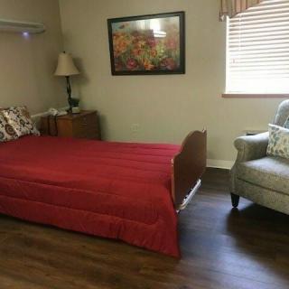 A cozy bedroom with a single bed, armchair, and decorative painting.