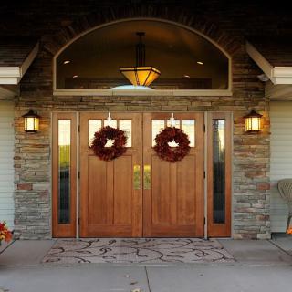 A welcoming entrance with double wooden doors adorned with wreaths, flanked by stone walls and lanterns.