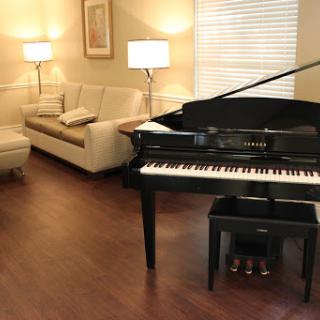 A cozy living room featuring a grand piano, a comfortable sofa, and warm lighting.