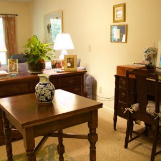 A cozy living room setup featuring wooden furniture, a decorative lamp, and a vibrant plant.