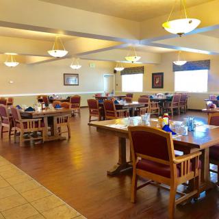 An empty dining room with neatly arranged tables and chairs under warm lighting.