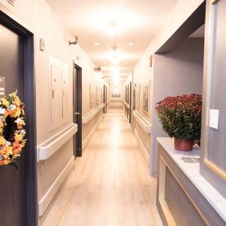 A well-lit hallway with decorative elements such as a wreath on the door and a potted plant on the counter.
