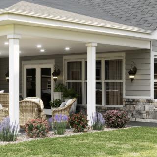 A cozy outdoor patio with wicker furniture, surrounded by a well-maintained garden.