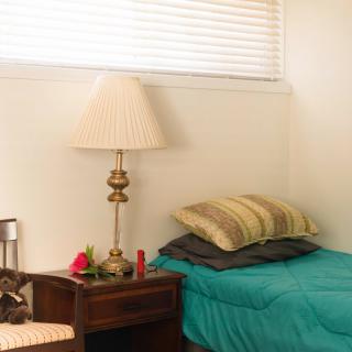 A cozy bedroom with a teal bedspread, nightstand, and lamp.