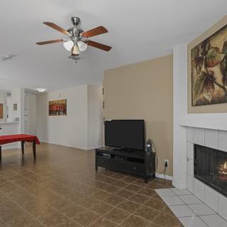 A cozy living room featuring a television, fireplace, and ceiling fan with artwork on the walls.