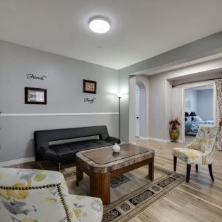A cozy living room featuring a black sofa, patterned armchairs, and a wooden coffee table, complemented by tasteful decorations and modern lighting.