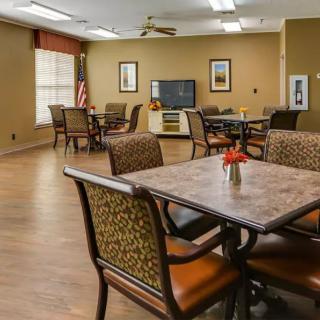 A communal dining area with several tables and chairs, a television, and decorative elements.