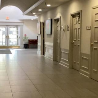 A well-lit hallway with several doors and a tile floor leading to an entrance.