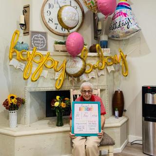 An elderly person celebrating their birthday with decorations and balloons.
