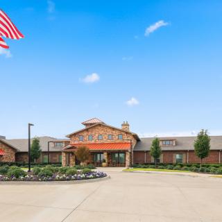 A large building with an American flag flying above, set against a clear blue sky.