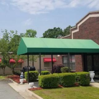 A building entrance with a green awning and well-maintained landscaping.