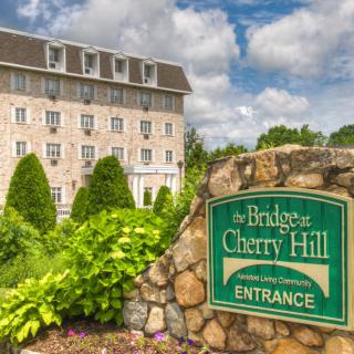 The exterior of a hotel with lush greenery and a prominent entrance sign.