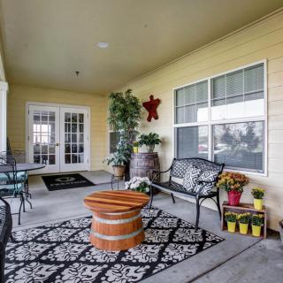 A cozy porch area with outdoor seating, a patterned rug, and decorative plants.