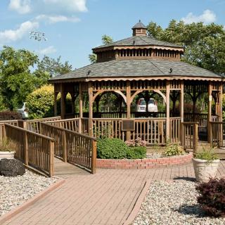 A beautiful wooden gazebo surrounded by a garden with a brick pathway leading to it.