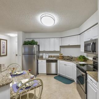 A modern kitchen with white cabinets and stainless steel appliances, complete with a small dining area.