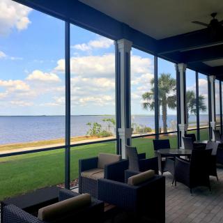 A scenic patio with outdoor seating overlooking a beautiful waterfront and palm trees.